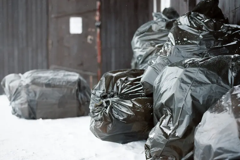 Shows bags in the snow against a fence